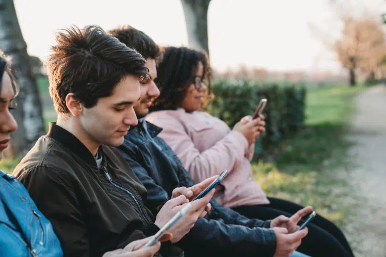 Multi ethnic group of friends using mobile phones outdoor